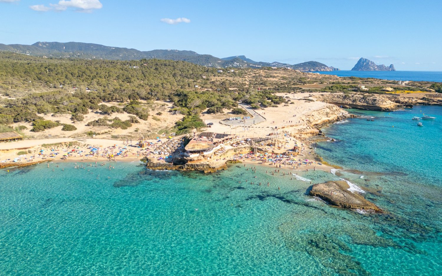 Cala Conta beach with clear turquoise water and sunbathers, Ibiza, Spain.