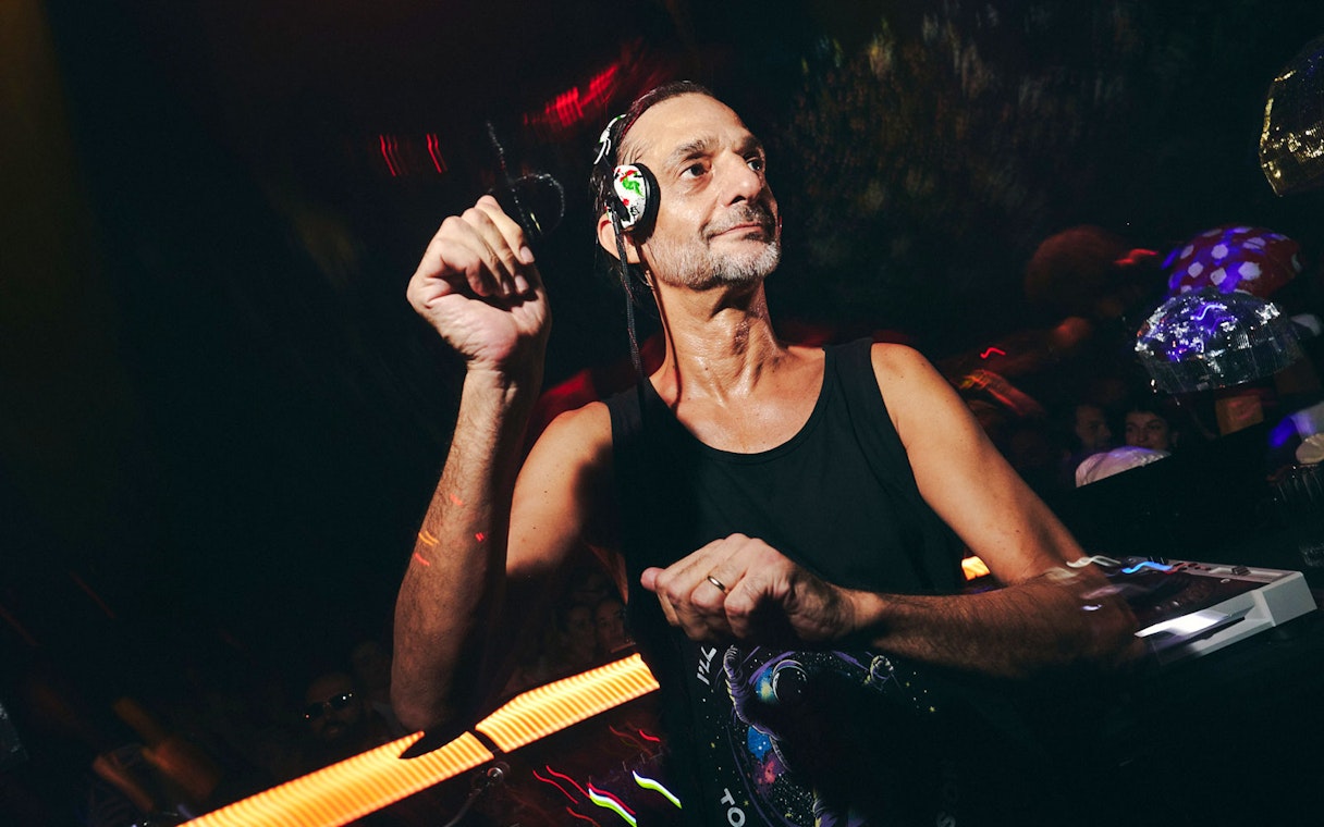 DJ performing at TRIP Club Chinois with vibrant lights and crowd in the background.