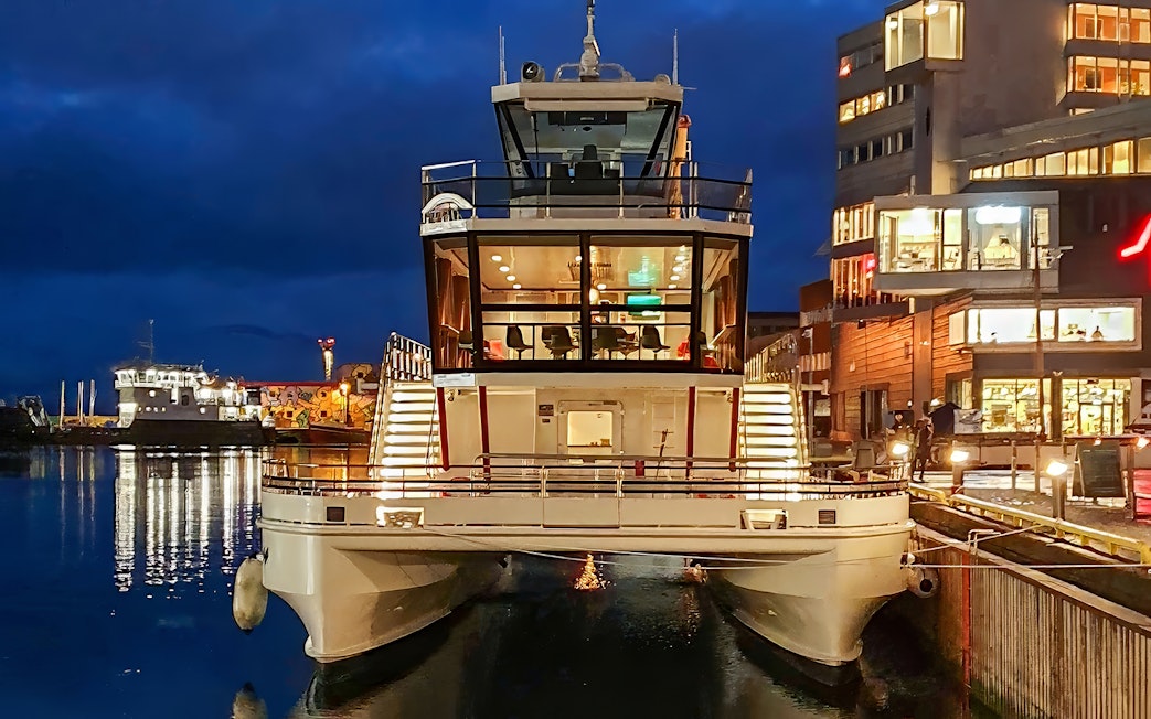 Electric cruise ship docked at night for Northern Lights tour.