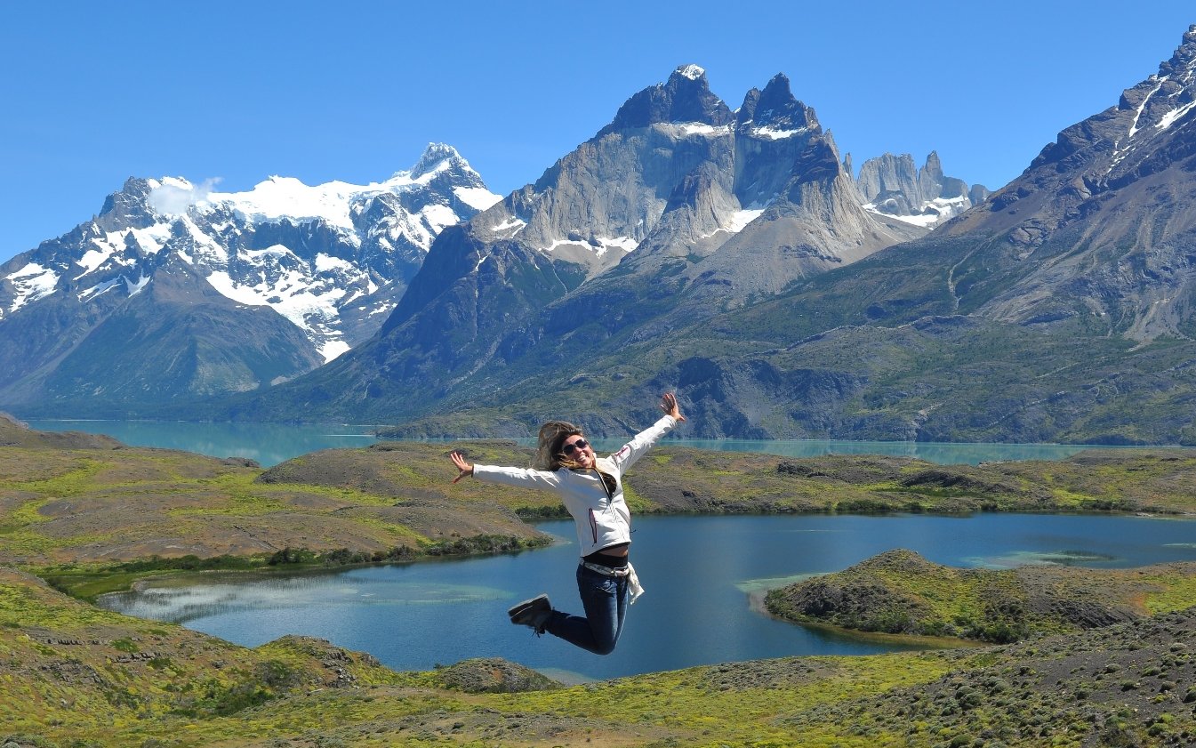 Tourist jumping in front of Cuernos del Paine, Torres del Paine National Park, Chile.