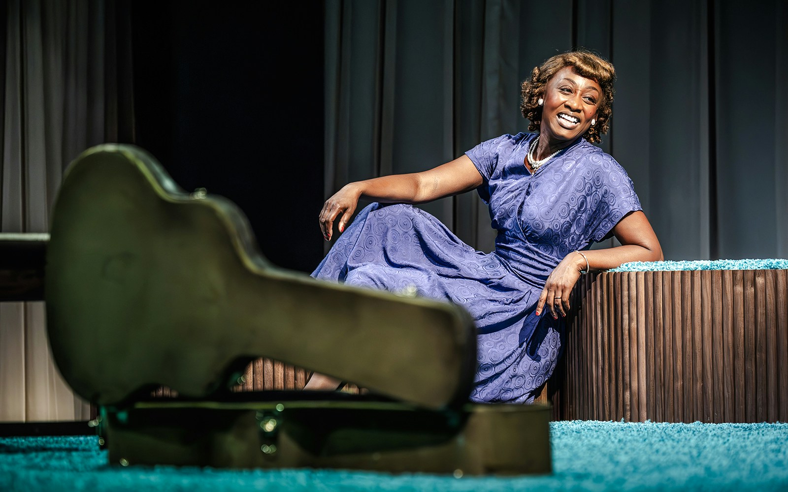 Performer in blue dress smiling on stage during Marie & Rosetta production.