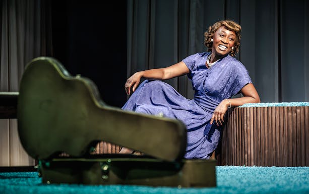 Performer in blue dress smiling on stage during Marie & Rosetta production.