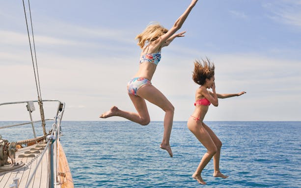 People jumping off a boat into the sea during a Half Day Athens Cruise.