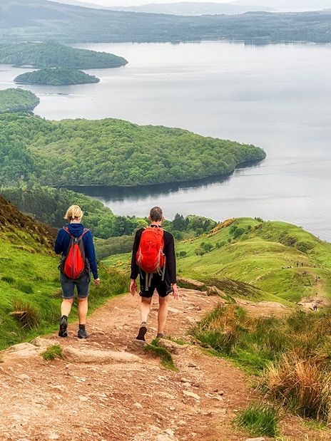 Hikers on a trail overlooking Loch Lomond, Scotland.