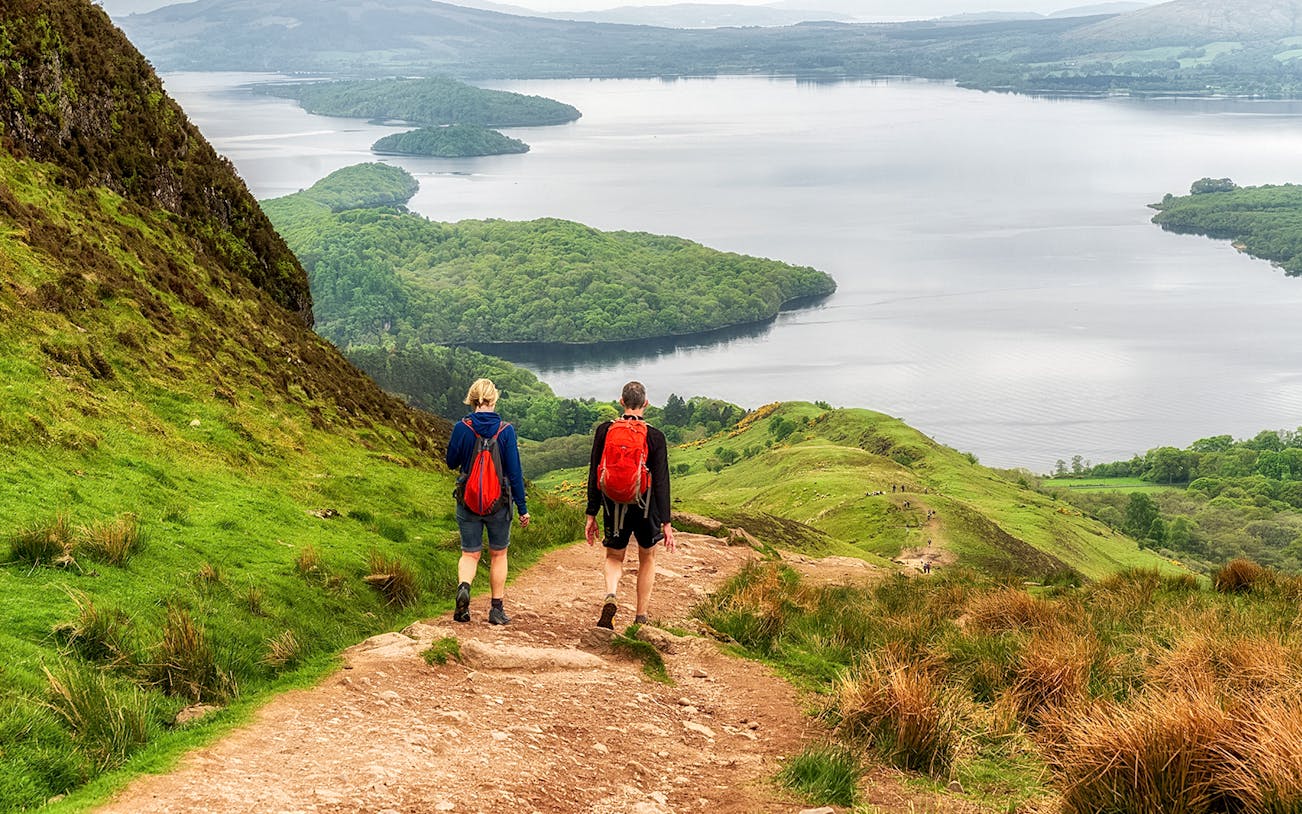 Hikers on a trail overlooking Loch Lomond, Scotland.