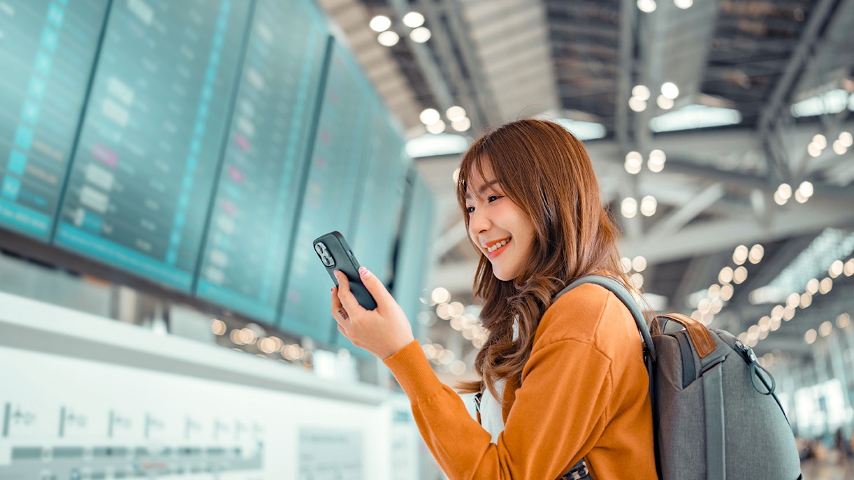 Traveller at airport checking phone for last-minute tickets to London attractions