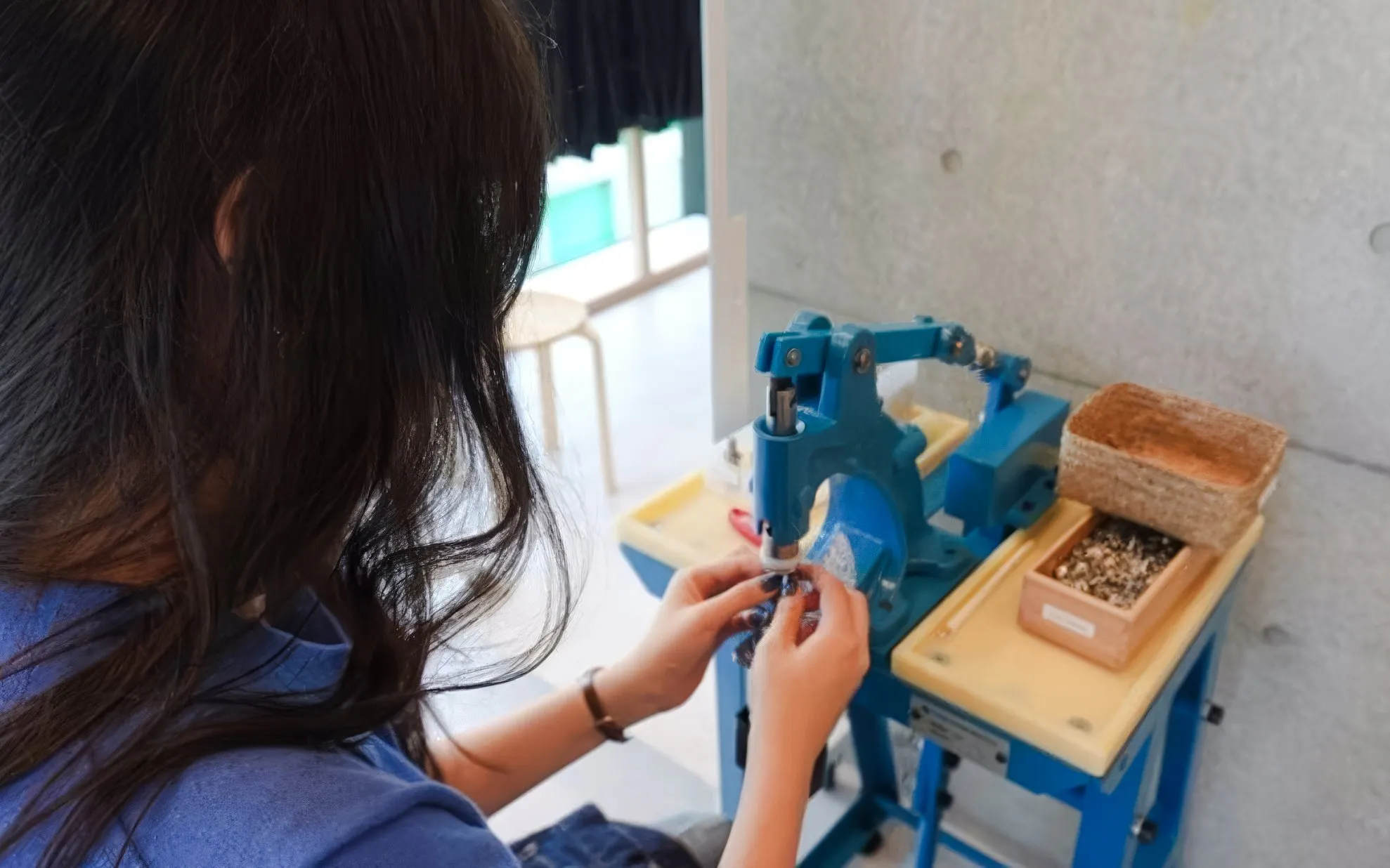 Woman crafting denim jeans at a machine during Tokyo Harajuku experience.