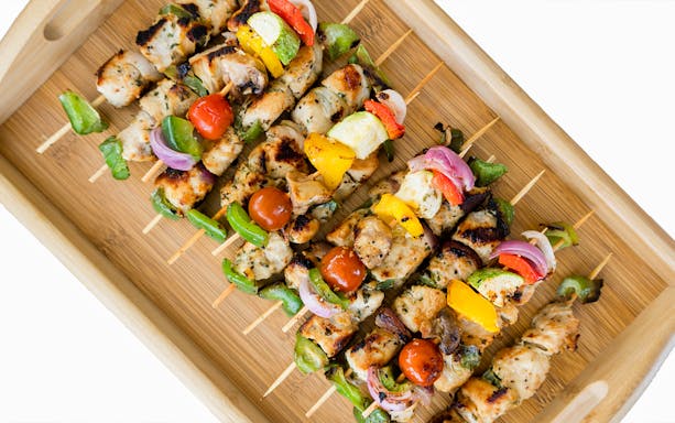 Grilled skewers with vegetables and chicken served on a wooden tray during Dubai yacht tour BBQ.