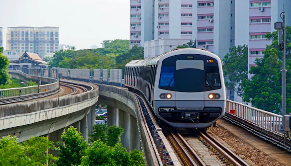 Singapore Metro train on elevated tracks with city buildings in the background.