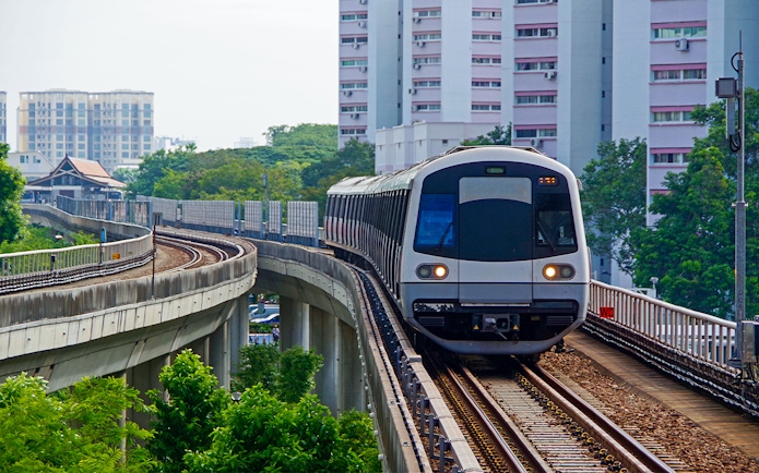 Singapore Metro train on elevated tracks with city buildings in the background.