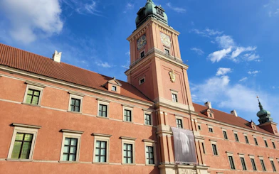 Warsaw Royal Castle exterior with clock tower under blue sky.