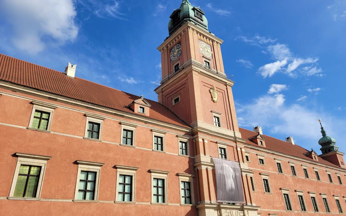 Warsaw Royal Castle exterior with clock tower under blue sky.