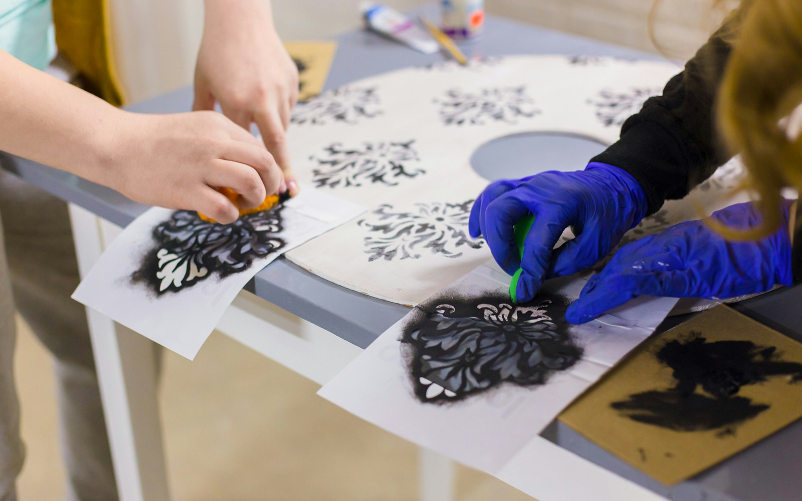 Woman wearing gloves and handpainting some stencil drawings