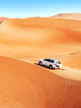 SUV driving over sand dunes in Dubai desert safari.