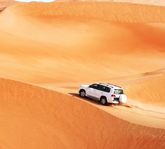 SUV driving over sand dunes in Dubai desert safari.