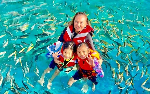 Snorkelers in Langkawi Marine Park surrounded by colorful fish.