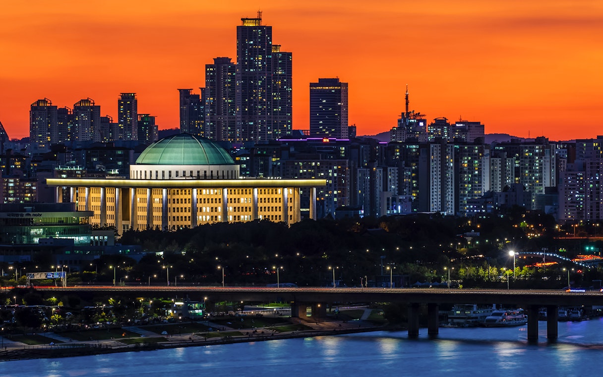 Seoul skyline at sunset with National Assembly building during Eland Cruise.