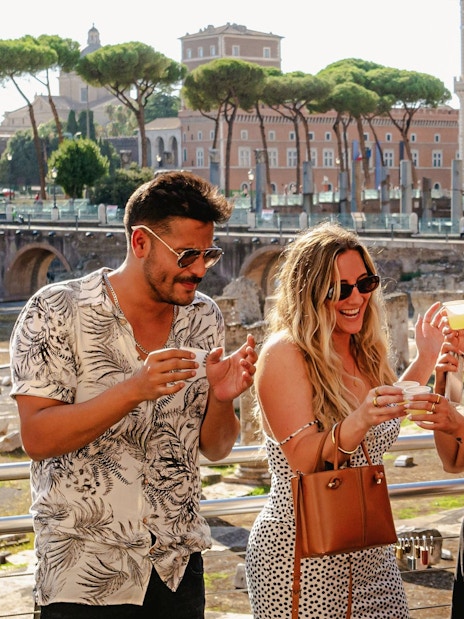 Guests enjoying drinks at the Tipsy Tour in Rome with ancient ruins in the background.