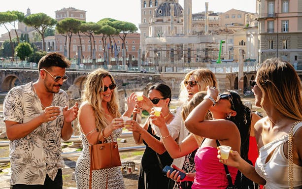 Guests enjoying drinks at the Tipsy Tour in Rome with ancient ruins in the background.
