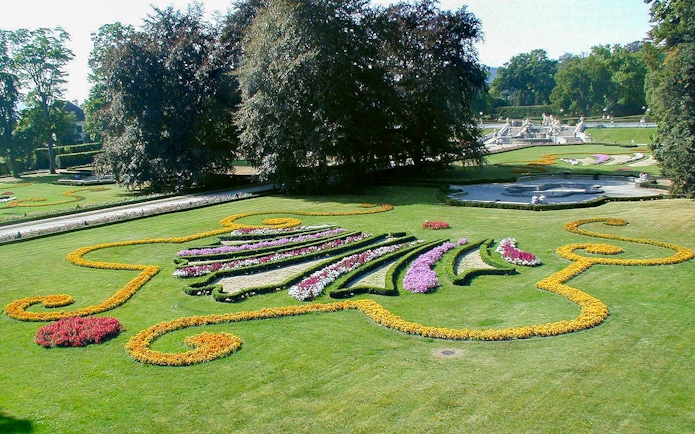 Cesky Krumlov castle gardens with colorful floral designs and manicured lawns.