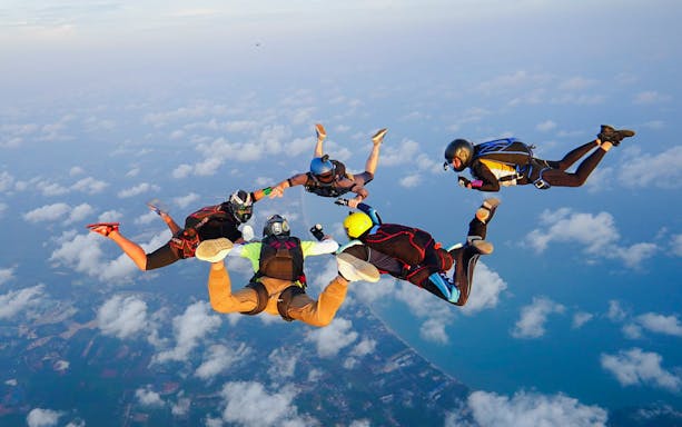 Skydivers in freefall over Pattaya coastline during tandem jump at 13,000 ft.