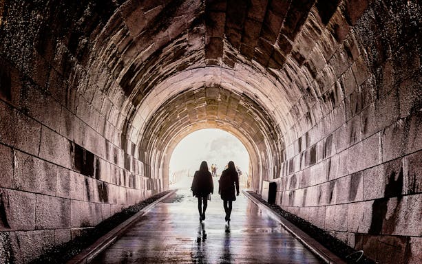 Tourists walking out of the Tailrace Tunnel towards daylight.