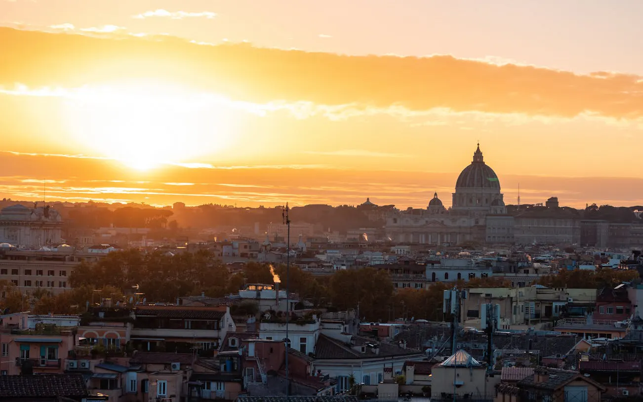 Rome skyline at sunset with St. Peter's Basilica in the distance.