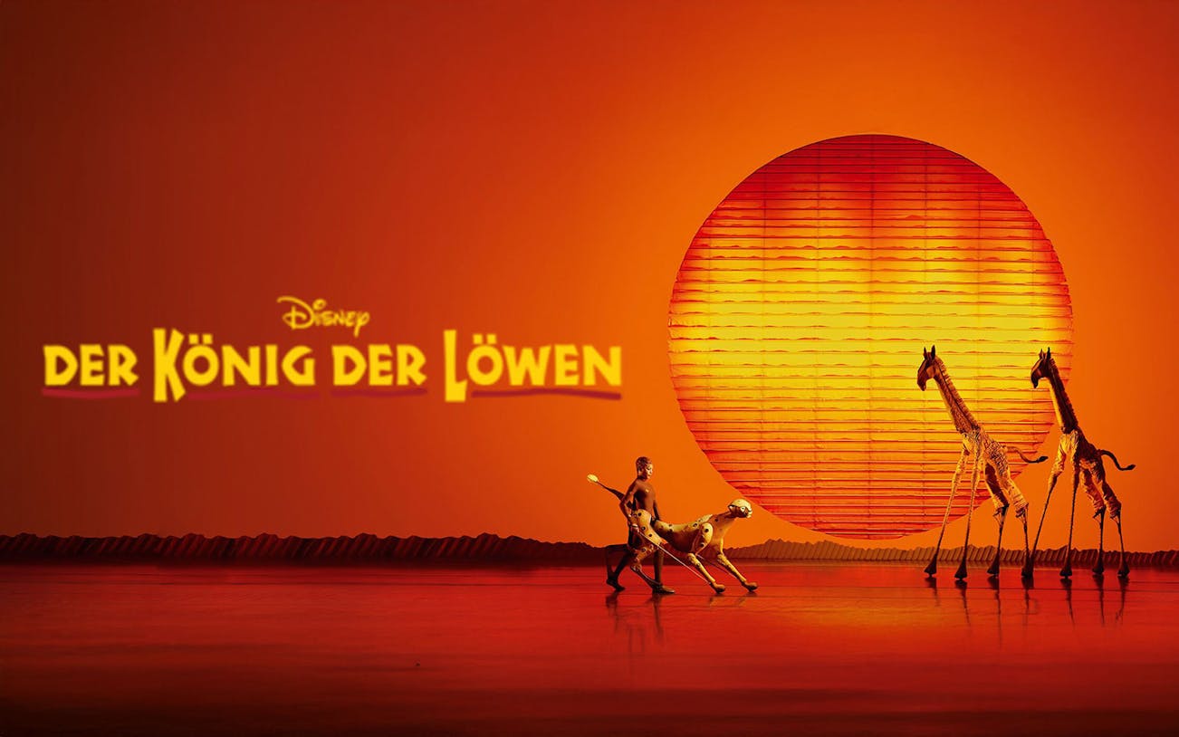 Stage scene from "Der König der Löwen" with performers and animal puppets against a sunset backdrop.