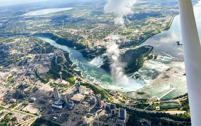 Aerial view of Niagara Falls with surrounding cityscape, highlighting the falls and river.