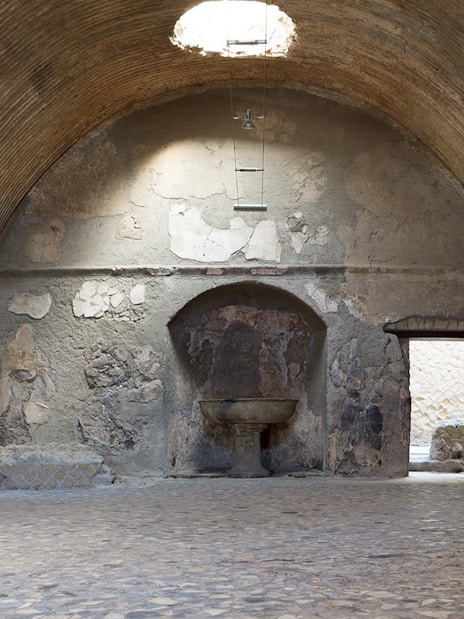 Central Baths interior at Herculaneum with vaulted ceiling and ancient stone basin.