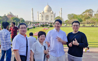 Visitors at the Taj Mahal with Agra Fort in the background during a guided day tour from Delhi.