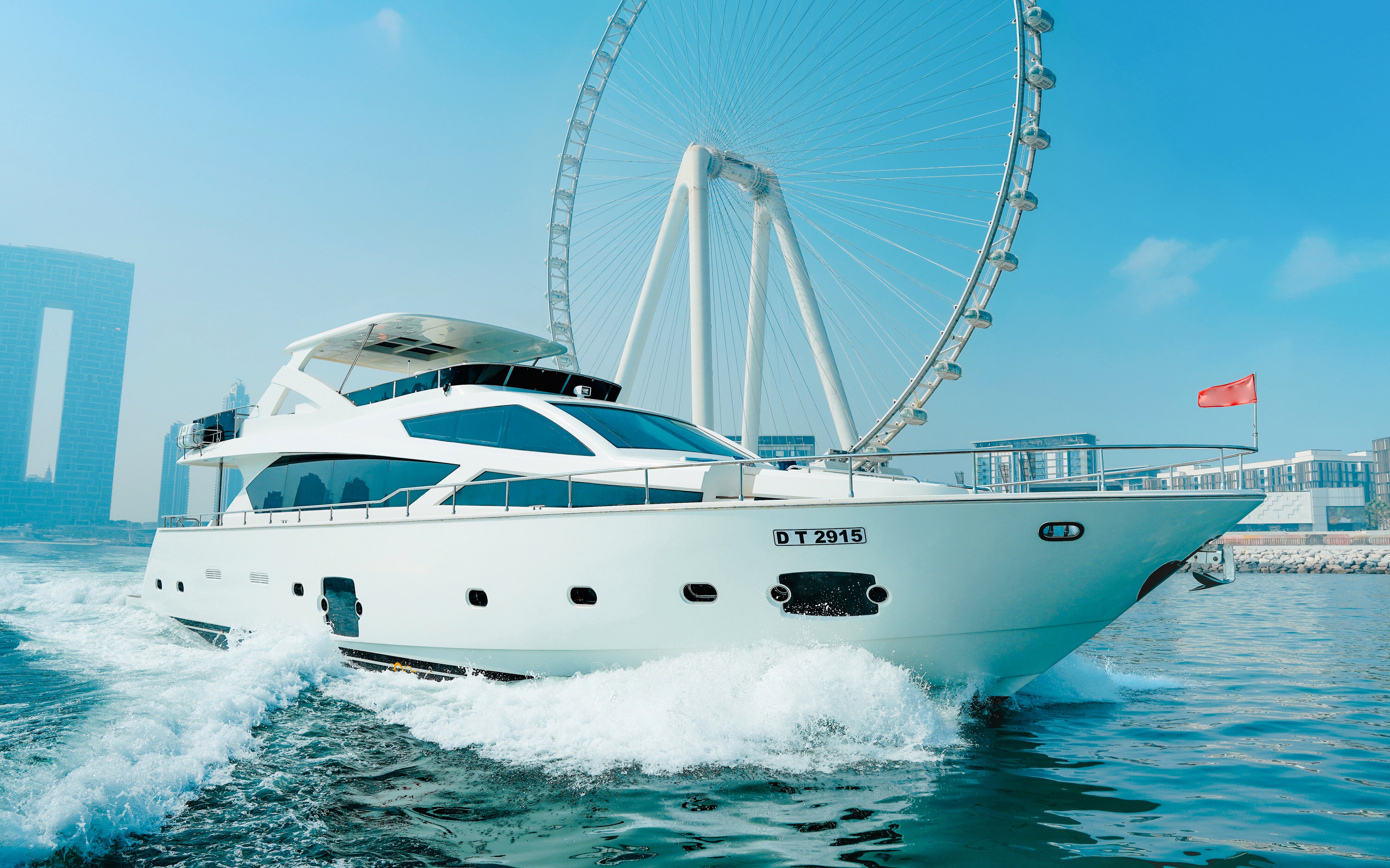 Luxury yacht cruising near Dubai Harbour with Ferris wheel in the background.