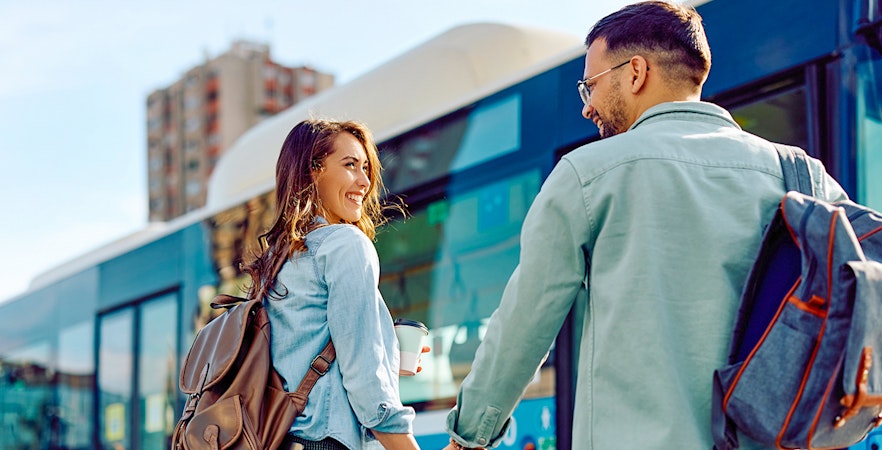 Couple holding hands near a blue bus, representing round trip transfers.