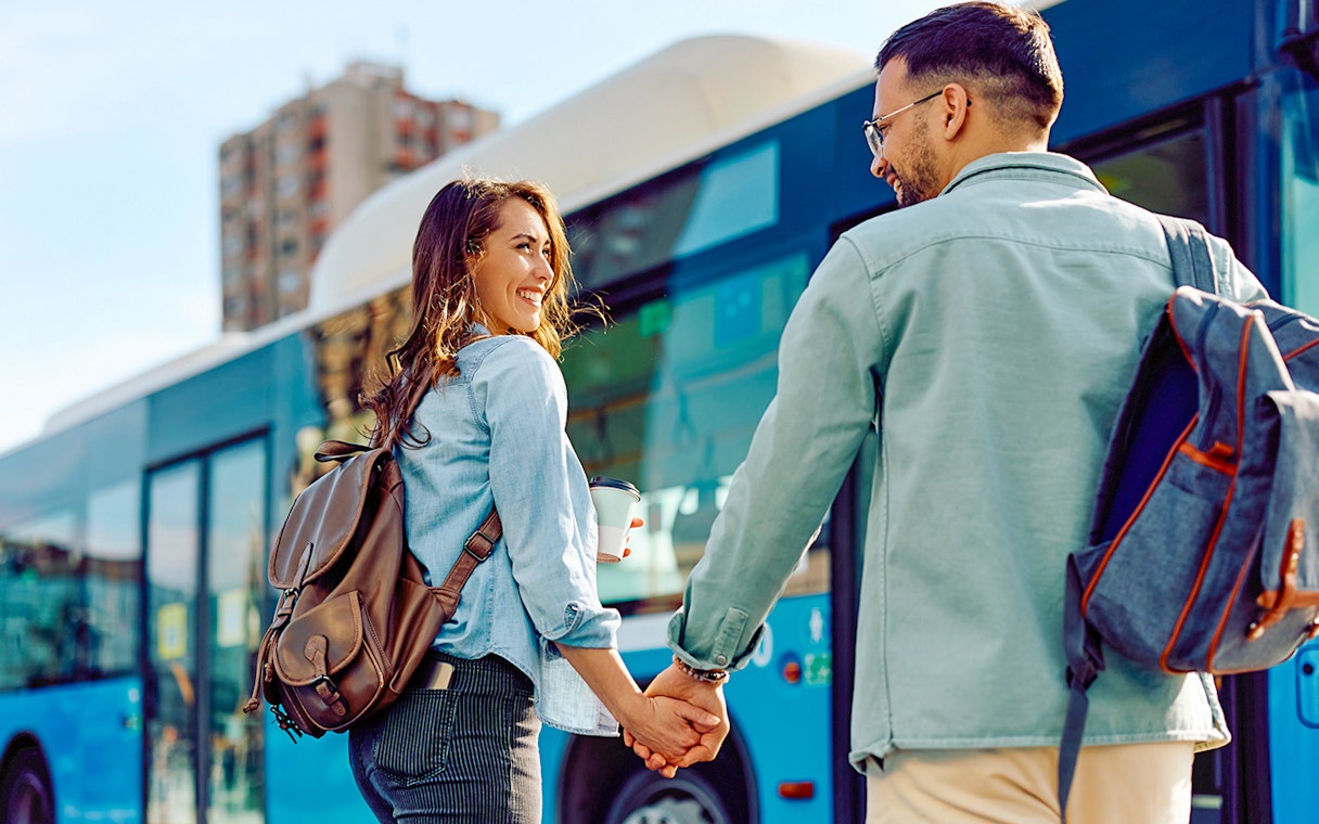 Couple holding hands near a blue bus, representing round trip transfers.