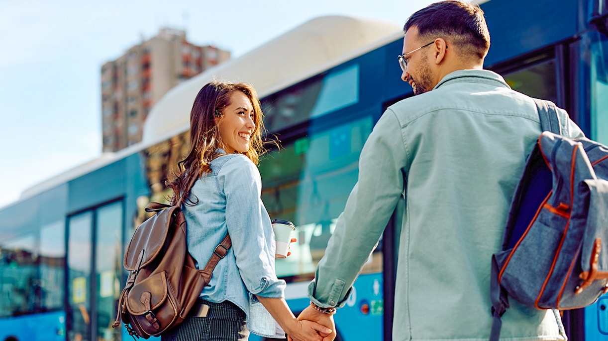 Couple holding hands near a blue bus, representing round trip transfers.