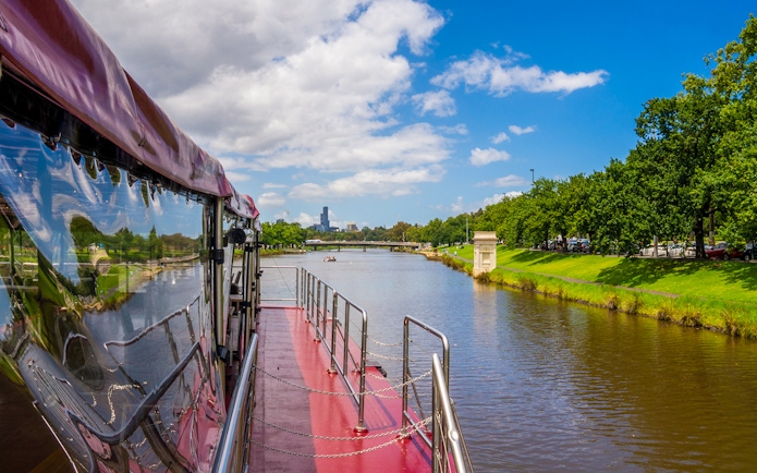Cruise boat on Yarra River with Melbourne skyline in the background.