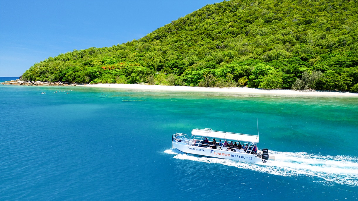 Glass bottom boat near Fitzroy Island, Australia, with lush greenery and clear blue water.