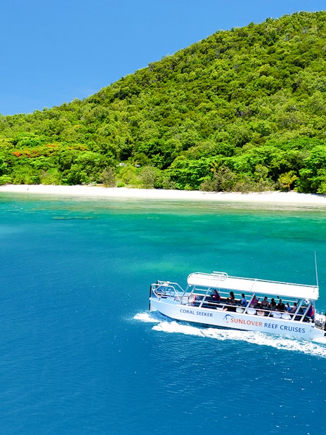 Glass bottom boat near Fitzroy Island, Australia, with lush greenery and clear blue water.