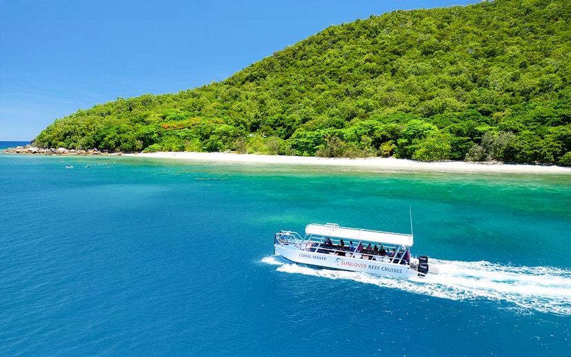 Glass bottom boat near Fitzroy Island, Australia, with lush greenery and clear blue water.