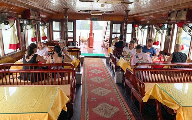 Guests dining inside Dragonfly Standard Cruise restaurant with scenic views.