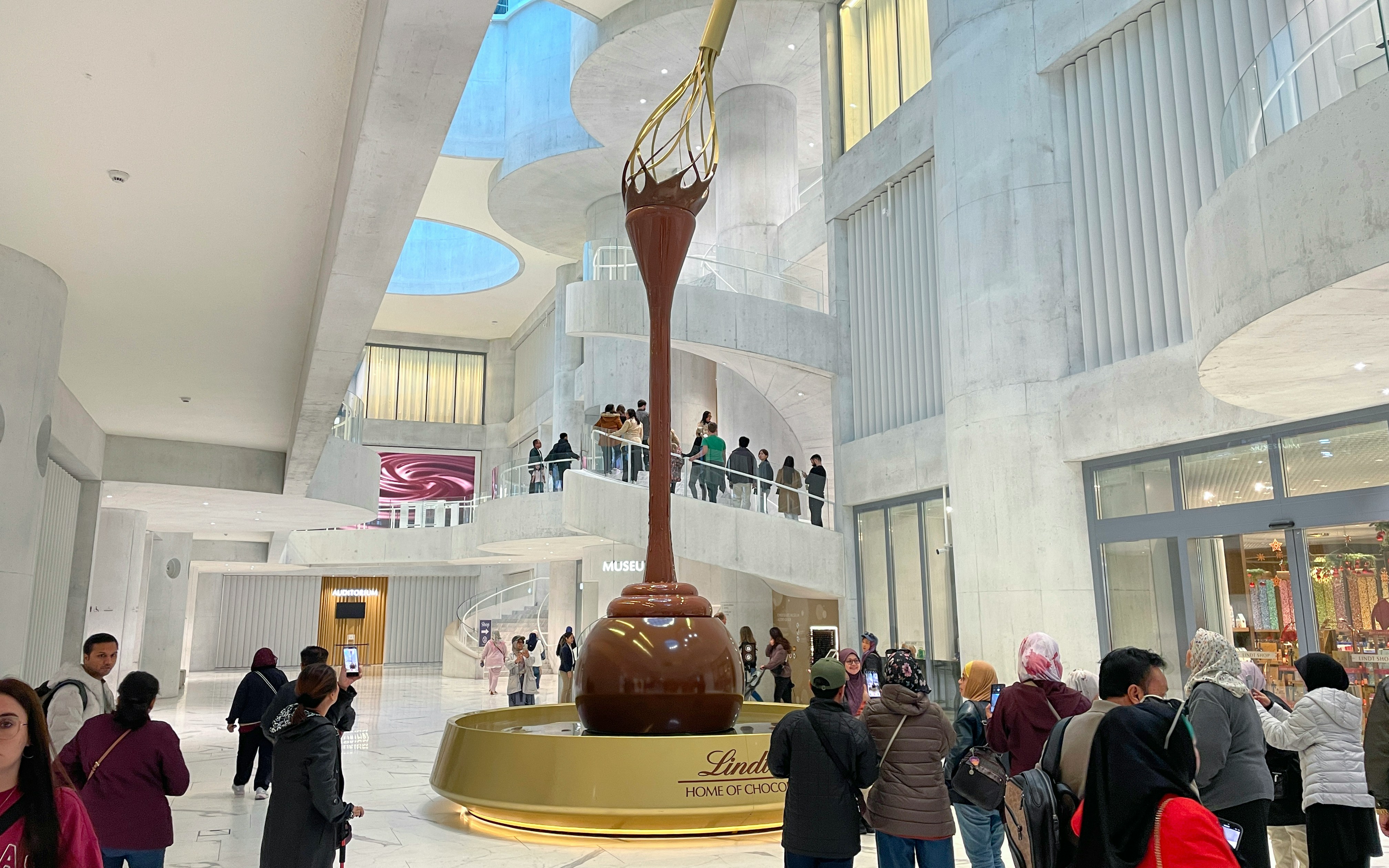 Lindt Home of Chocolate Museum Zurich interior with large chocolate fountain and visitors.