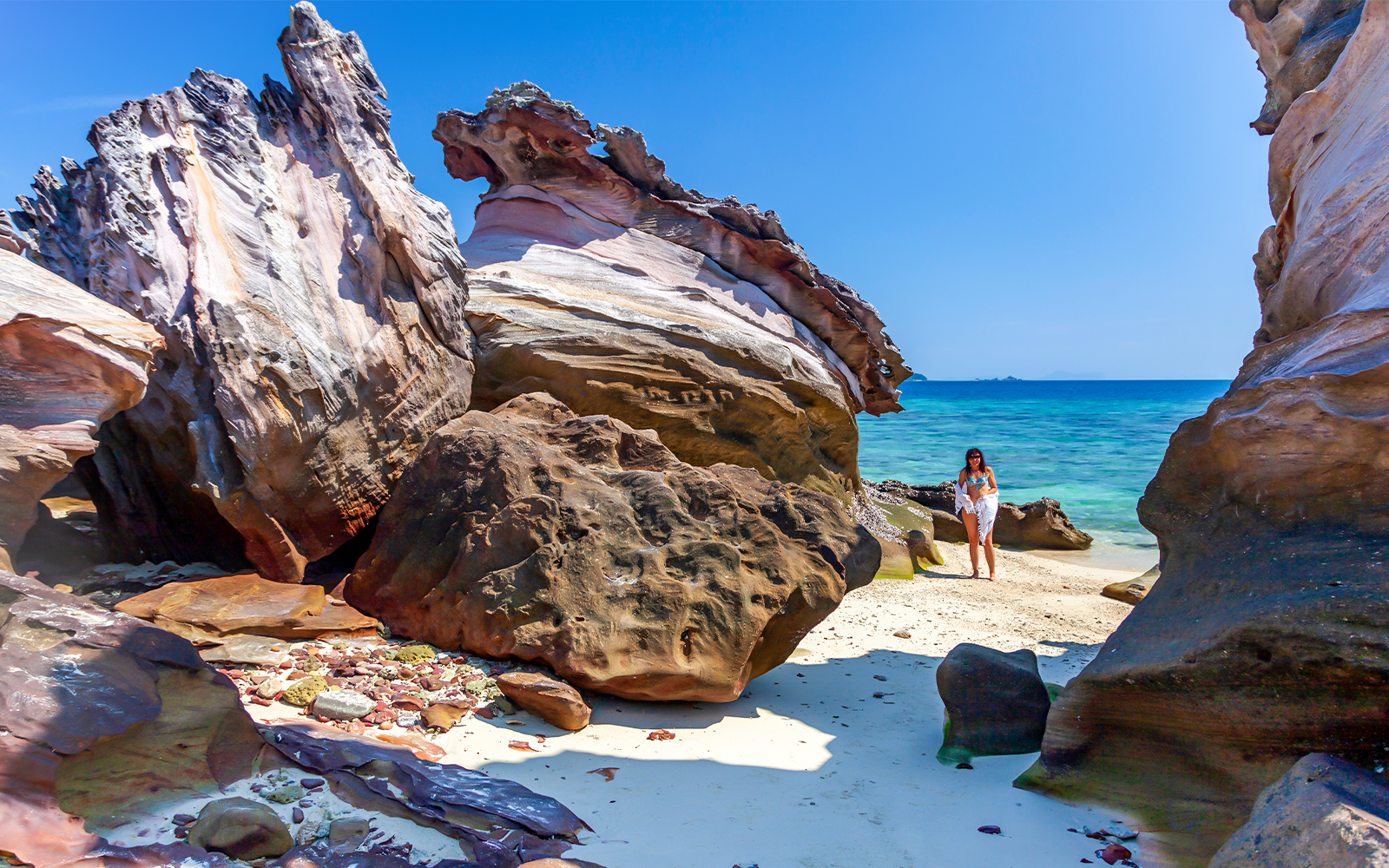 Khai Nok Island beach with clear waters and rocky shoreline, Phuket province, South Thailand.