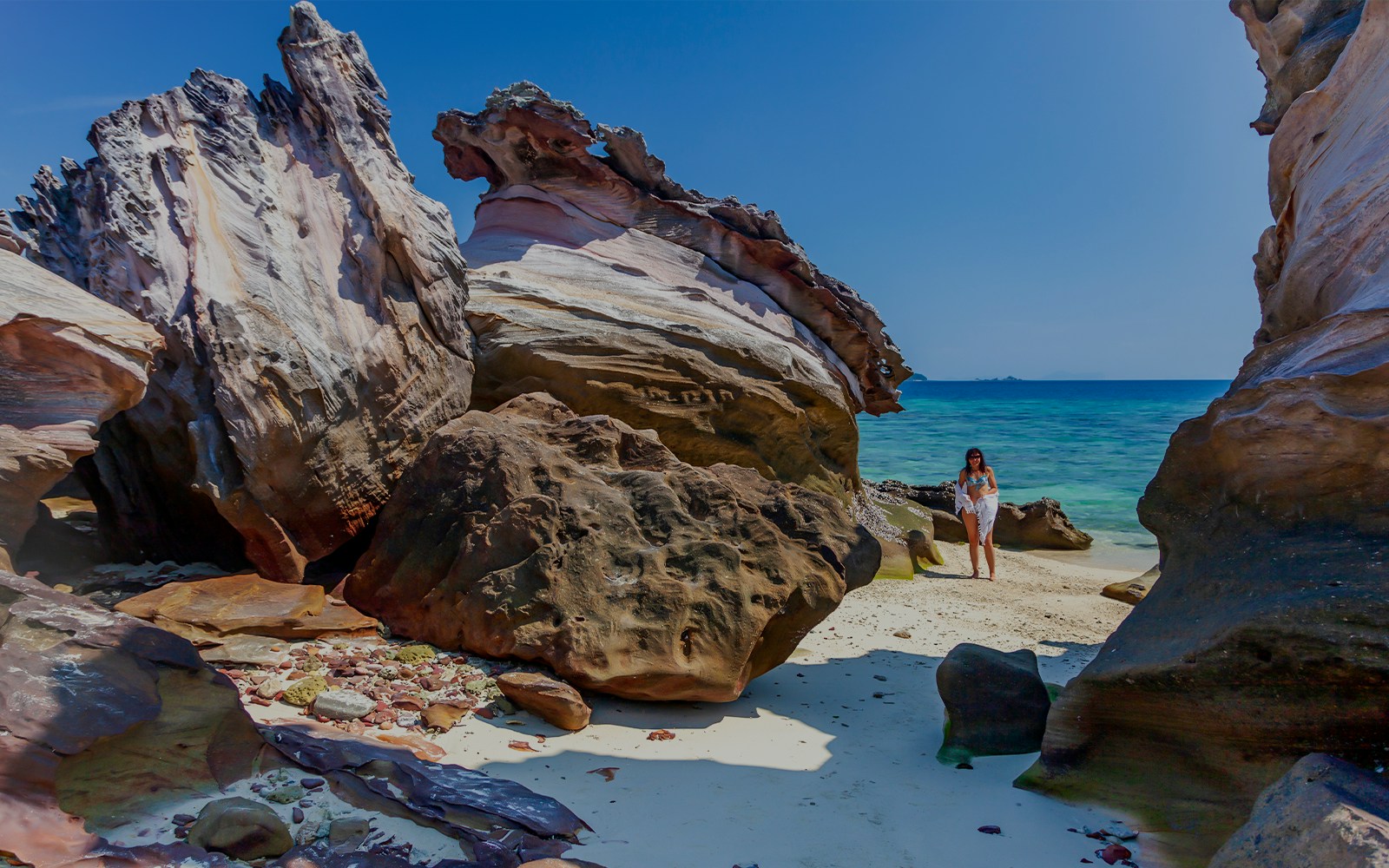 Khai Nok Island beach with clear waters and rocky shoreline, Phuket province, South Thailand.