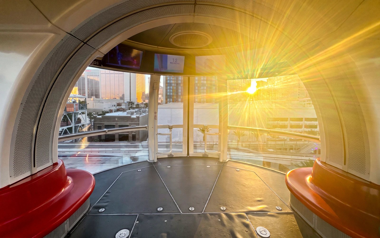 Spacious cabin interior of the High Roller in Las Vegas with city view at sunset.