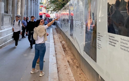 Tourists exploring a historical exhibit on a Paris street during a guided tour.
