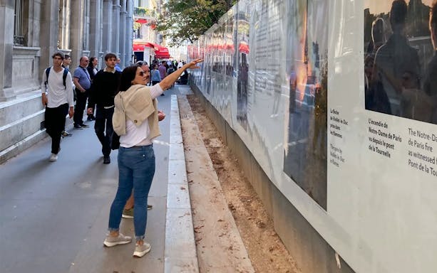 Tourists exploring a historical exhibit on a Paris street during a guided tour.