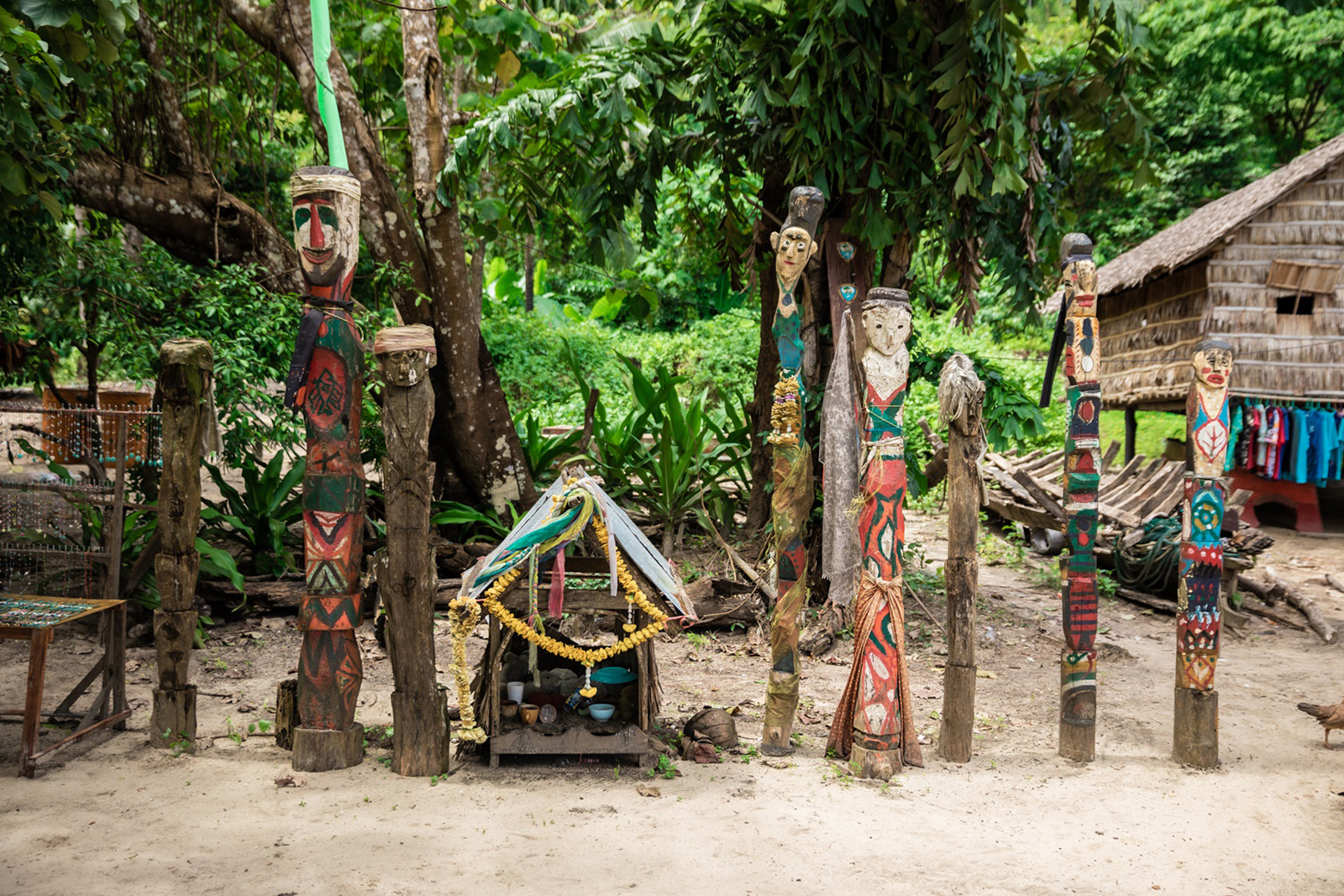 Colorful carved wooden totems and small shrine in Surin Islands village setting.