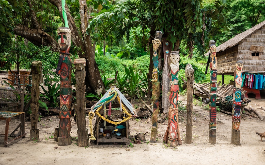 Colorful carved wooden totems and small shrine in Surin Islands village setting.