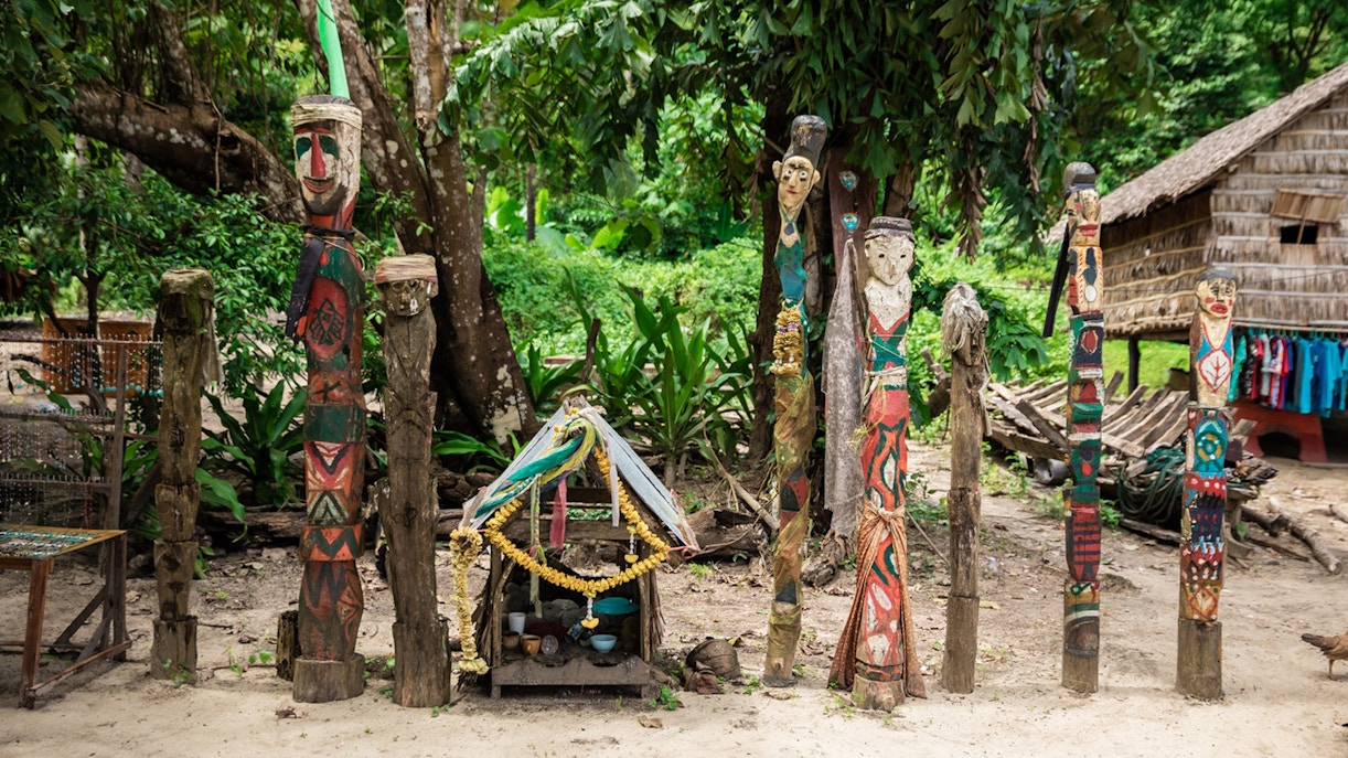 Colorful carved wooden totems and small shrine in Surin Islands village setting.
