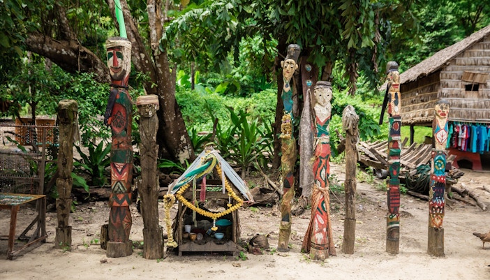 Colorful carved wooden totems and small shrine in Surin Islands village setting.